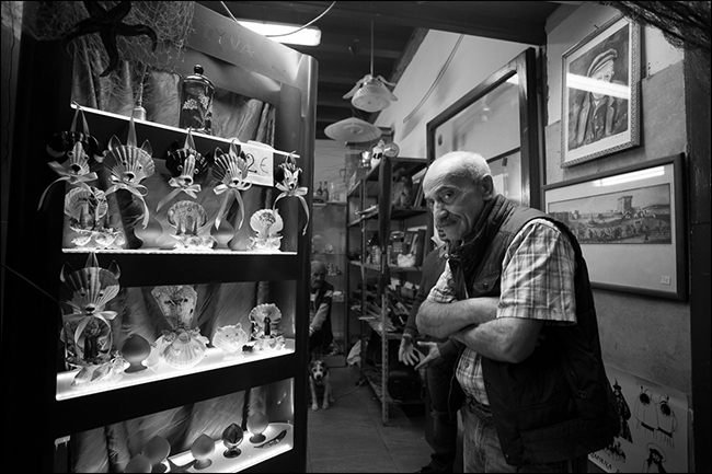 Uomo anziano con le braccia conserte nel negozio di curiosità