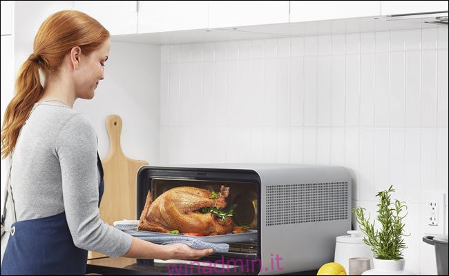 Donna che prende un tacchino di cottura da un forno intelligente di giugno