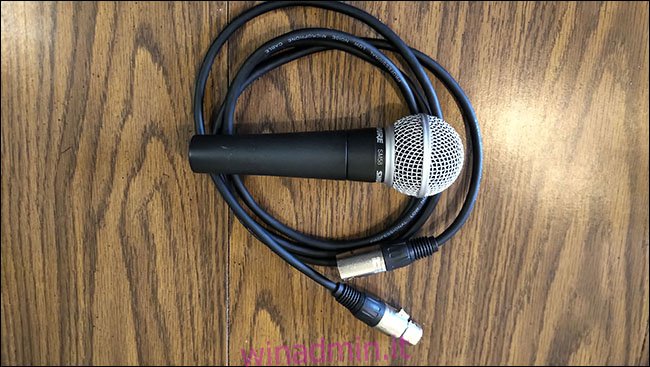 Un microfono Shure SM58 posizionato su un cavo XLR AmazonBasics su un tavolo.