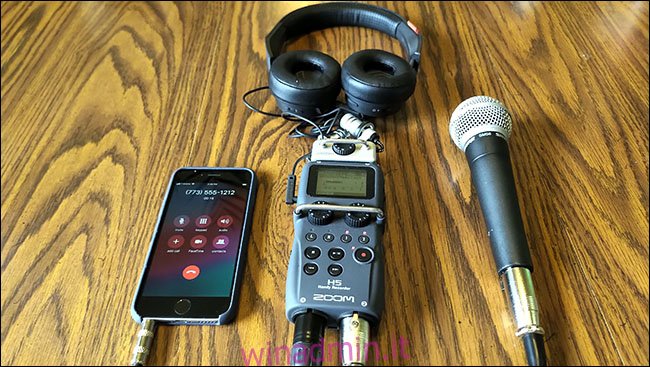 Un iPhone, un microfono Shure SM58 e le cuffie sono tutti collegati a un registratore Zoom H5, adagiato su un tavolo.