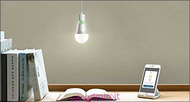 Una lampadina Wi-Fi TP-Link appesa su un libro aperto e un telefono cellulare su una scrivania.
