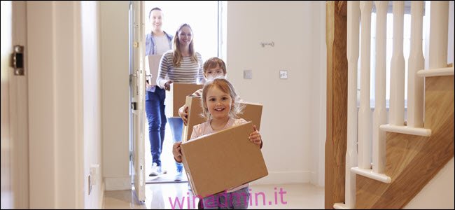 Una famiglia felice che trasporta scatole in una casa.