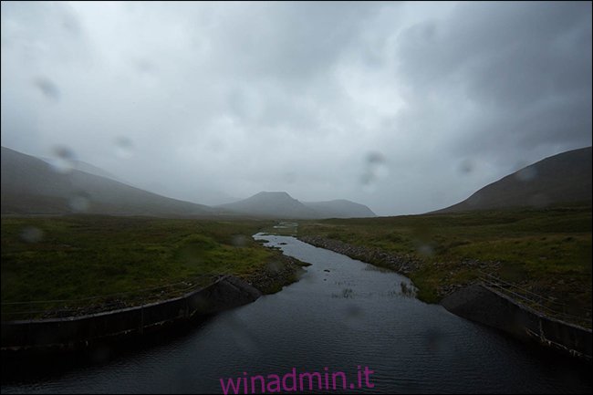 Una foto piovosa di una montagna e di un ruscello con goccioline d'acqua sulla lente. 