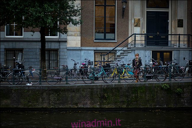 Una donna in piedi su un ponte dietro una fila di biciclette parcheggiate.