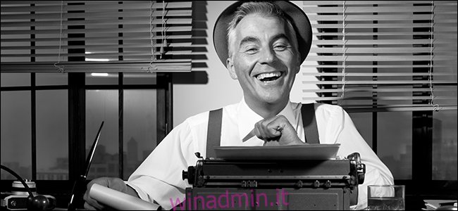 Un vecchio giornalista ride dietro una macchina da scrivere.