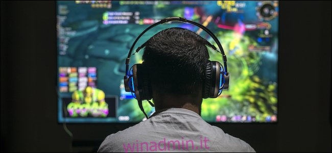 Un uomo che gioca ai videogiochi su un monitor ultra-ampio, mentre indossa le cuffie.