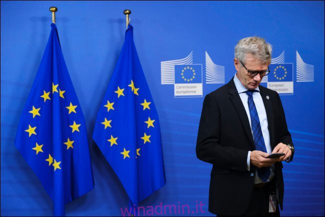 Un uomo che utilizza uno smartphone con due bandiere dell'UE dietro di lui.